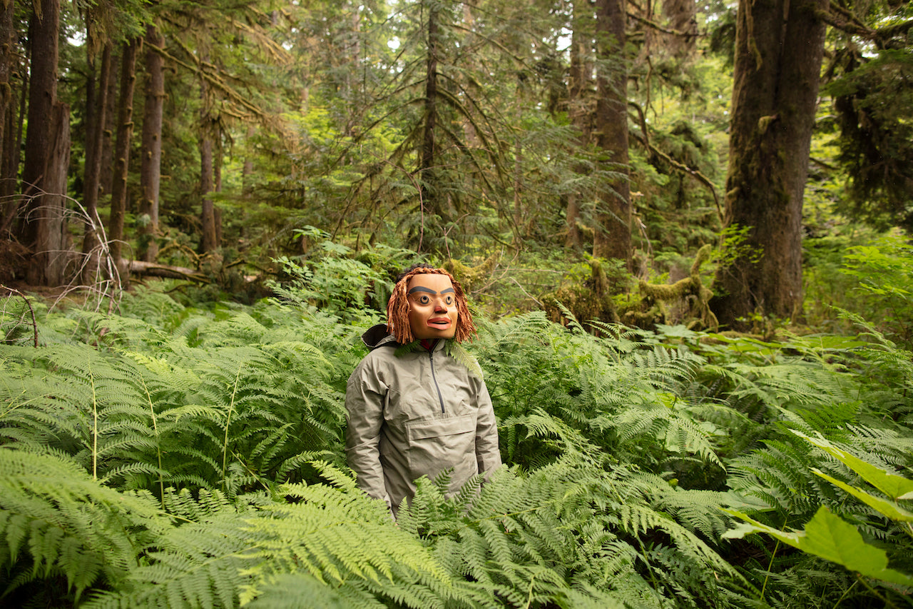 Rande Cook wears his handmade forest bathing mask and Anorak Jacked in Sage while standing in an old growth patch with ferns.