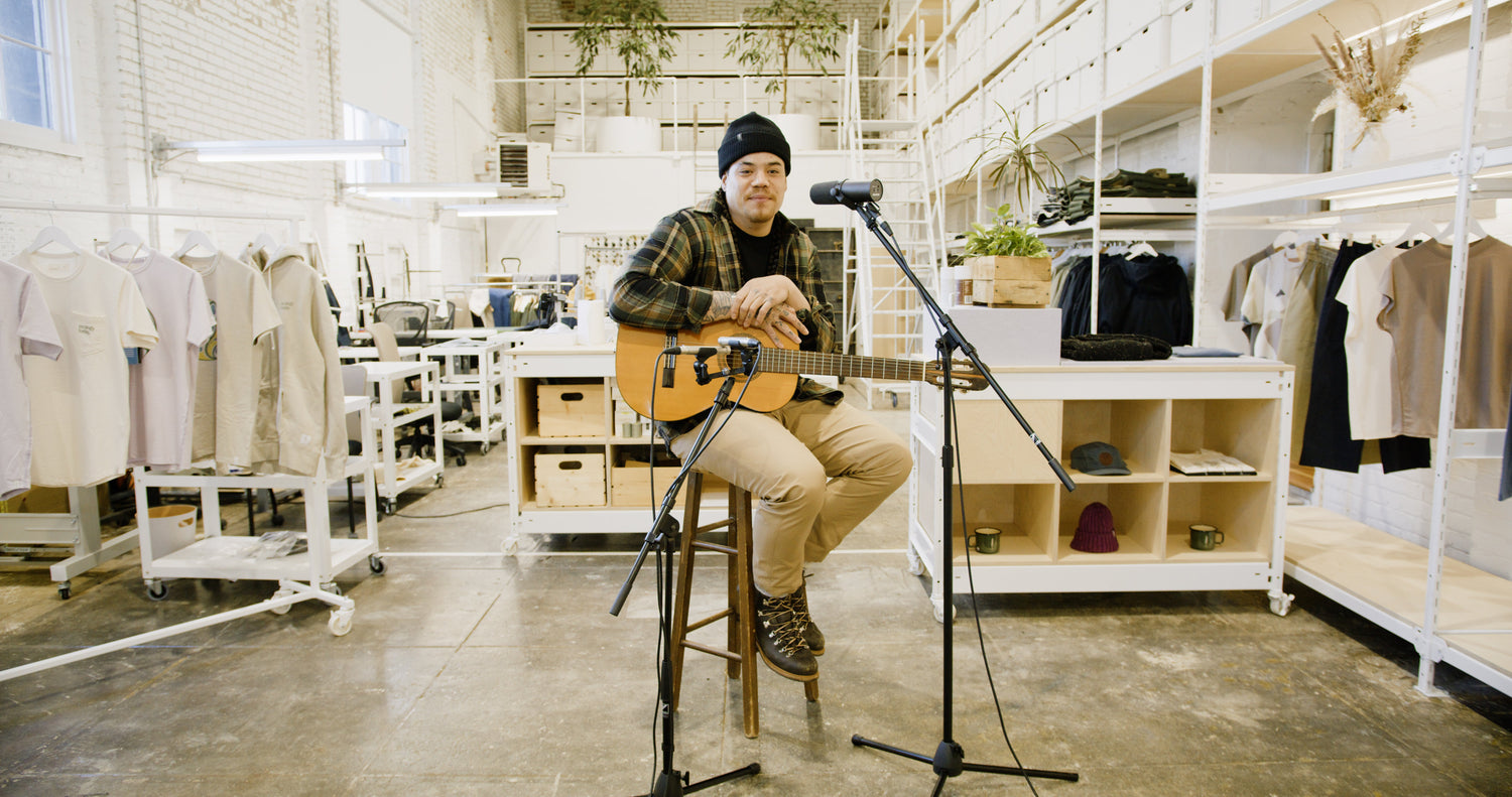 Logan Staats sits playing his guitar at the ecologyst Factory and HQ